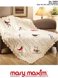 a white crocheted blanket with birds on it