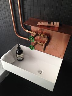 a bathroom sink with copper faucet and soap dispenser next to it