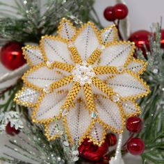 a white and yellow brooch sitting on top of a christmas tree