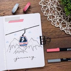 an open notebook with a drawing of a ski lift on it and some markers next to it