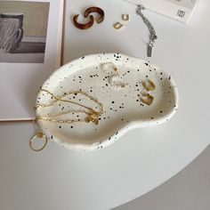 a white plate with black speckles sitting on top of a table next to other items