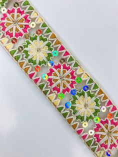 a white ribbon with multicolored flowers and sequins on the side,