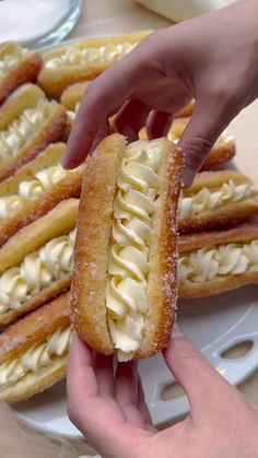 a person holding a pastry in front of other desserts on a plate with forks