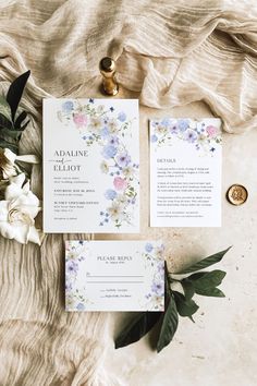 the wedding stationery is laid out on top of a table with flowers and greenery