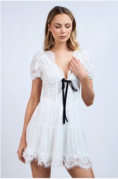 Flaunt your sweet and sassy side in the Te Amo Lace Mini Dress. Made from soft lace and a sheer lined layered fabric, this dress features a flattering neckline adorned with a black velvet bow tie detail. The open back also has a contrast tie that adds a playful touch. Perfect for showing off your unique style! Color: White Mini Length Floral Embroidered Lace Flattering NeckLine With Scalloped Edge Lace Short Puff Sleeve Contrast Front Velvet Tie Bow Open Back With Velvet Tie Bow Scalloped Lace Hemline Lined Fabric 100% Polyester Feminine Mini Dress With Contrast Lace For Party, Coquette Lace Trim Dress For Date Night, Lace Mini Dress For Date Night, Flirty Lace Dress For Brunch, Coquette Lace Bodice Dress, Lace Bodice Coquette Dress, Delicate Lace Mini Dress For Daywear, Fitted Coquette Dress With Contrast Lace, Fitted Dress With Contrast Lace