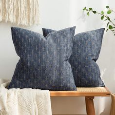 two blue pillows sitting on top of a wooden bench next to a potted plant