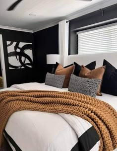 a bedroom with black walls and white bedding is decorated in gold, black and white