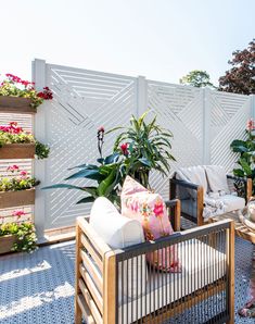 an outdoor living area with potted plants on the side and a couch in the middle