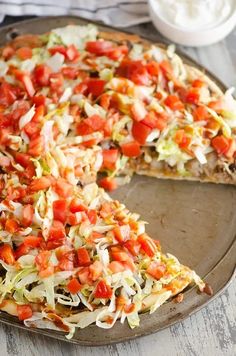 an easy taco pizza with shredded cheese, tomatoes and lettuce on top