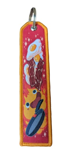 a red and yellow key chain with an image of bacon, eggs and pancakes on it