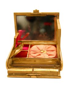 the inside of a gold case with pink and orange items in it on a white surface