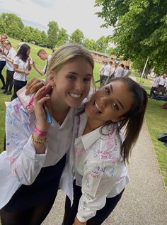 two girls are posing for the camera in front of some other people and one girl is smiling