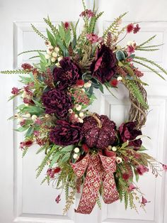 a wreath with purple flowers and greenery hangs on a door