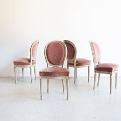 four chairs with pink velvet upholstered back rest in front of a white wall