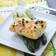 a white plate topped with fish and asparagus