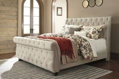 a white bed sitting on top of a wooden floor next to a rug and window