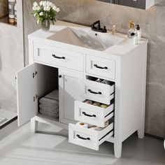 a white bathroom vanity with drawers and a sink in it's center, next to a mirror