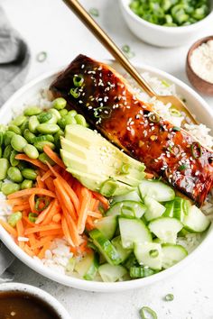 a bowl filled with rice, carrots, cucumbers and other veggies