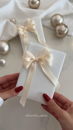 a woman's hands holding a white gift box with a bow