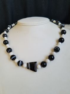 "This vintage Black Banded Sardonyx beaded necklace is strung onto a white cord and closed of with a silver tone lobster clasp. The stones are in a round medium size with the exception of the middle stone that is shaped in an odd triangle. The small round white stones are Moonglow Stones. The pattern is White alternates with the Black sandwiched between the Whites stones. The necklace is sturdy and in excellent vintage condition. The necklace will arrive in a gift box with FREE SHIPPING. Measure White Hand-strung Round Necklaces, Onyx Large Beads Jewelry For Gifts, White Agate Necklace With Round Beads, Onyx Jewelry With Large Beads As Gift, Vintage White Gemstone Beads Jewelry, Vintage White Jewelry With Gemstone Beads, White Agate Jewelry With Polished Beads, Adjustable Hand-strung Onyx Necklace, Vintage White Hand-strung Jewelry