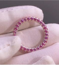 a pink diamond ring sitting on top of a white glove