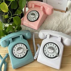 three old - fashioned telephones are sitting on a table next to a teddy bear