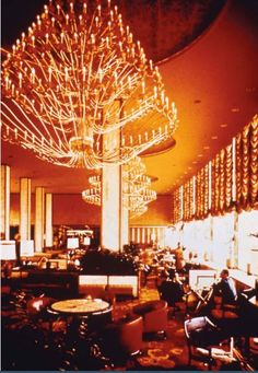 a fancy chandelier hangs from the ceiling in a large room filled with tables and chairs