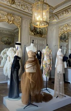 mannequins and dresses on display in an ornate room