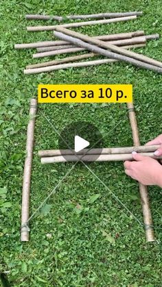 a person is making a wooden structure out of sticks and wood dows on the grass