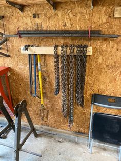 there are many chains hanging on the wall next to chairs and ladders in this garage