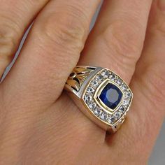 a person's hand with a gold and blue ring on it