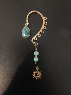 a pair of gold hoop earrings with turquoise beads and a sun charm hanging from it