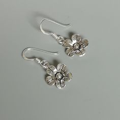 A PAIR of sterling silver flower ear danglers. Dimensions: 10 x 10 mm Drop length:22 mm Weight: 1.42 gm Price listed is for a PAIR of hoops. These earrings are made of 925 hypoallergenic sterling silver and comes with a 925 stamp. Can be packaged in a gift box. I can include a personal message from you if needed You are welcome to contact me at... bhavnakwintra1956@gmail.com For more beautiful pieces from my shop, please browse 👇 TOE RINGS: https://www.etsy.com/your/shops/TheSilverGame/tools/li Silver Flower Jewelry With Matching Earrings, Silver Flower Earrings For Pierced Ears, Silver Flower Earrings For Gift, Sterling Silver Flower Charm Earrings, Silver Sterling Flower Pendant Earrings, Sterling Silver Flower Earrings In White Gold, Elegant Silver Flower Pendant Earrings, Silver Flower Charm Earrings, Silver Pierced Flower Earrings For Gift