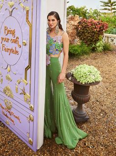 Make a statement with our moss green one-shoulder top, lavishly adorned with hand-embroidered 3D flowers, beads, and crystals. Paired with a matching georgette gharara, this ensemble offers a perfect blend of glamour and sophistication for any occasion. Green Hand Embellished Bollywood Sharara, Green Embellished Sharara For Party, Hand Embellished Green Bollywood Sharara, Bollywood Style Hand Embellished Green Sharara, Glamorous Festive Green Sets, Green Georgette Party Wear Sets, Green Embellished Party Wear Sets, Green Festive Palazzo Set For Party, Festive Green Palazzo Set For Party