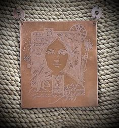 a metal plaque with a woman's face on it hanging from a roped wall