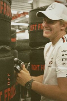 a man in a white shirt is smiling and holding a black object with red writing on it