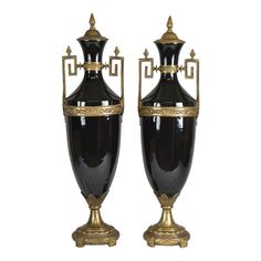 two black and gold vases sitting side by side on top of each other in front of a white background