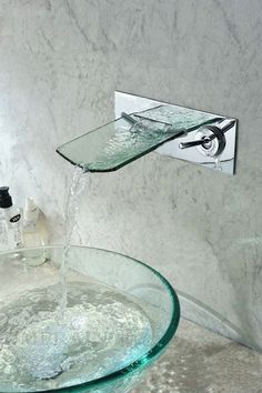 a glass sink with water running from the faucet