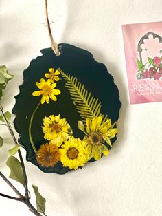 some yellow flowers are sitting on a black piece of paper next to a pink card