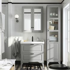 a white bathroom with gray cabinets and black and white checkered floor