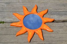 an orange sun shaped mirror sitting on top of a wooden table