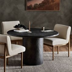 a round table with chairs around it and a painting on the wall behind it in a dining room