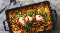 a casserole dish with sour cream, tomatoes and other toppings on top