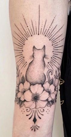 a black and white photo of a cat with flowers on it's leg, in front of a wall