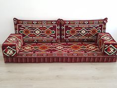 a red couch sitting on top of a hard wood floor next to a white wall