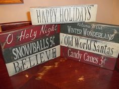 three wooden signs that say happy holidays and have snowballs in them on a table