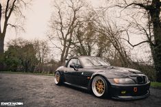 a black sports car parked in front of some trees