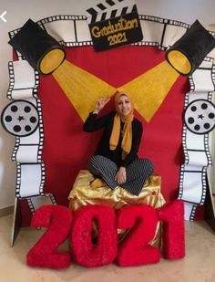 a woman sitting on top of a chair in front of a red and yellow backdrop