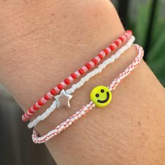 seed bead bracelet with a yellow smiley face bead. black stripes, red stripes and pink strung on elastic please gently roll on and off to prolong its life handmade in venice, ca Everyday Red Friendship Bracelets With Colorful Beads, Everyday Red Friendship Bracelet With Round Beads, Playful Red Beaded Bracelets, Fun Red Beaded Bracelet, Cute Red Friendship Bracelets With Round Beads, Red Friendship Bracelets With Round Beads, Red Adjustable Fun Beaded Bracelets, Cute Red Beaded Friendship Bracelets, Cute Red Beaded Bracelets With Round Beads