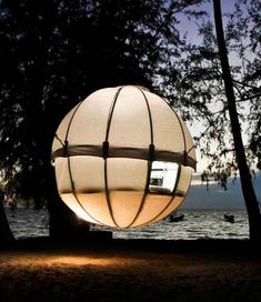 a large white ball sitting on top of a sandy beach next to the ocean at night